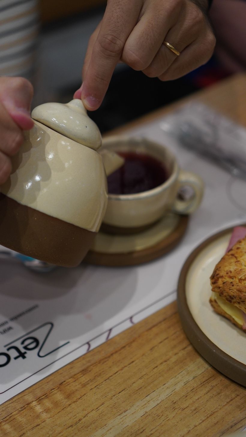 Tetera de cerámica y un scon de jamón y queso sobre el individual de Zeta